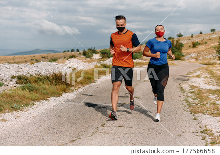 Couple running in nature at morning wearing protective face masks 127566658