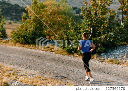 Empowered Runner Embracing Nature's Beauty on a Serene Morning Trail. 127566678