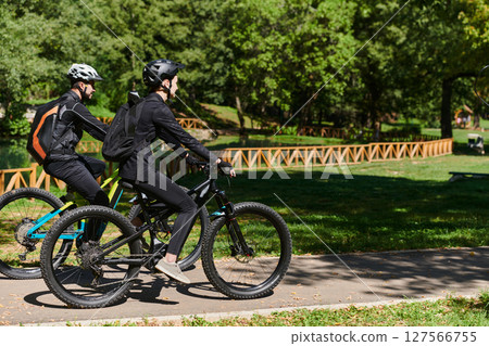 A blissful couple, adorned in professional cycling gear, enjoys a romantic bicycle ride through a park, surrounded by modern natural attractions, radiating love and happiness A blissful couple, adorned in professional cycling gear, enjoys a romantic bicycle ride through a park, surrounded by modern natural attractions, radiating love and happiness 127566755