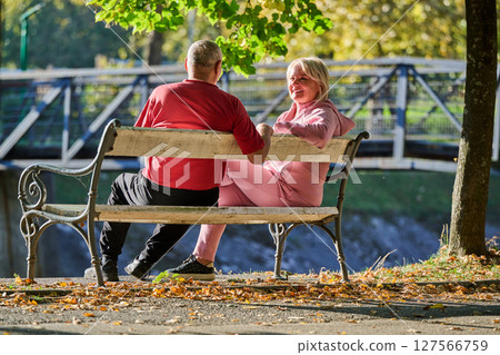 Elderly couple finding solace and joy as they rest on a park bench, engaged in heartfelt conversation, following a rejuvenating strol a testament to the enduring companionship and serene connection Elderly couple finding solace and joy as they rest on a park bench, engaged in heartfelt conversation, following a rejuvenating strol a testament to the enduring companionship and serene connection 127566759