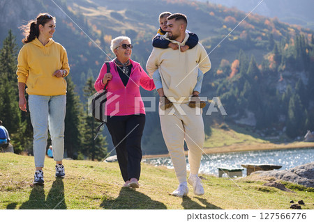 A family shares delightful moments with their friends amid the stunning landscapes of mountains, lakes, and winding paths, promoting a healthy lifestyle and the joy of familial bonds in the embrace of 127566776