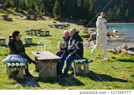 A family shares delightful moments with their friends amid the stunning landscapes of mountains, lakes, and winding paths, promoting a healthy lifestyle and the joy of familial bonds in the embrace of 127566777