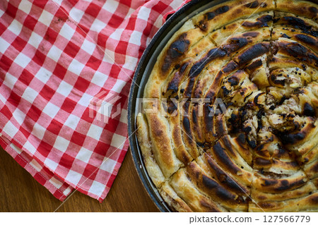 Exquisitely prepared, this traditional Bosnian dish showcases a mouthwatering pie under its lid, perfectly baked and ready to delight guests, embodying the rich culinary heritage and inviting flavors 127566779