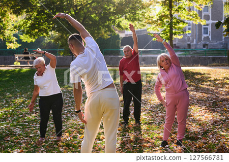 A group of seniors follows a trainer, engaging in outdoor exercises in the park, as they collectively strive to maintain vitality and well-being, embracing an active and health-conscious lifestyle in A group of seniors follows a trainer, engaging in outdoor exercises in the park, as they collectively strive to maintain vitality and well-being, embracing an active and health-conscious lifestyle in 127566781