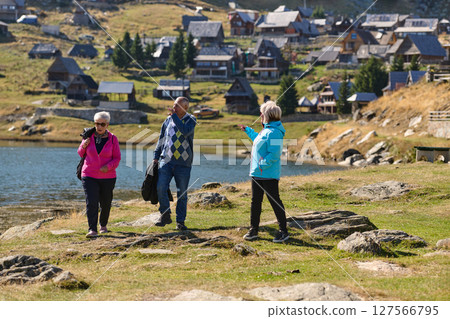 A family shares delightful moments with their friends amid the stunning landscapes of mountains, lakes, and winding paths, promoting a healthy lifestyle and the joy of familial bonds in the embrace of 127566795