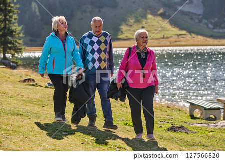 A family shares delightful moments with their friends amid the stunning landscapes of mountains, lakes, and winding paths, promoting a healthy lifestyle and the joy of familial bonds in the embrace of 127566820
