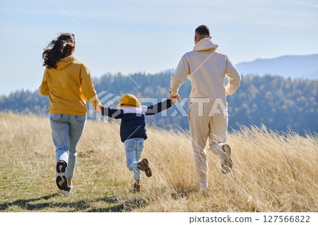 A modern family, along with their son, revels in the joy of a muddy day in nature, running and playing together, encapsulating the beauty of a healthy and active lifestyle 127566822
