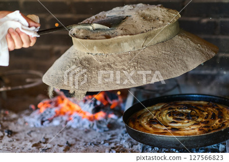 Capturing the essence of Bosnian culinary tradition, step-by-step preparation of a traditional Bosnian pie, showcasing the meticulous craftsmanship and authentic flavors involved in the culinary 127566823