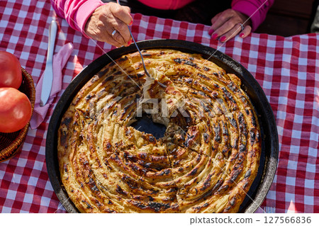 Exquisitely prepared, this traditional Bosnian dish showcases a mouthwatering pie under its lid, perfectly baked and ready to delight guests, embodying the rich culinary heritage and inviting flavors 127566836