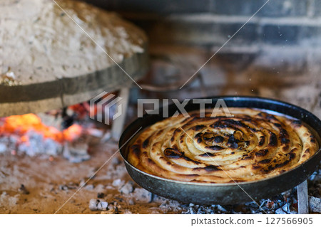 Capturing the essence of Bosnian culinary tradition, step-by-step preparation of a traditional Bosnian pie, showcasing the meticulous craftsmanship and authentic flavors involved in the culinary 127566905