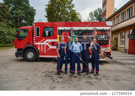 A skilled and dedicated professional firefighting team proudly poses in front of their state of the art firetruck, showcasing their modern equipment and commitment to ensuring public safety. 127566914