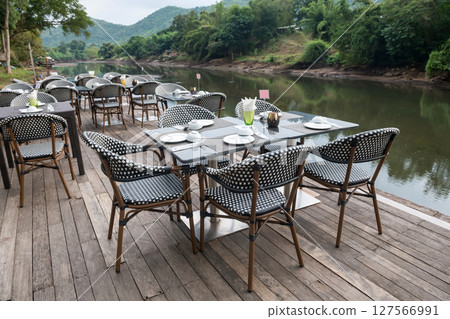 Outdoor restaurant table on wood terrace by kwai river, Kanchanaburi Outdoor restaurant table on wood terrace by kwai river, Kanchanaburi 127566991