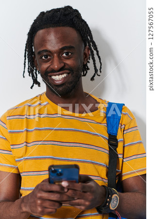 African American teenager engages with his smartphone against a pristine white background, encapsulating the essence of contemporary digital connectivity and youth culture 127567055
