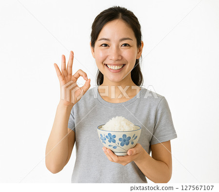 A woman holding a flower-patterned rice bowl and making an OK pose with a smile 127567107