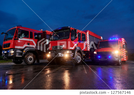 A pair of highly modern and quality fire trucks illuminate the night with their rotating lights, symbolizing the cutting-edge technology and preparedness of the firefighting fleet, ready to respond to 127567146