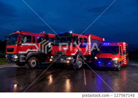 A pair of highly modern and quality fire trucks illuminate the night with their rotating lights, symbolizing the cutting-edge technology and preparedness of the firefighting fleet, ready to respond to 127567148