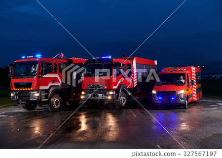 A pair of highly modern and quality fire trucks illuminate the night with their rotating lights, symbolizing the cutting-edge technology and preparedness of the firefighting fleet, ready to respond to A pair of highly modern and quality fire trucks illuminate the night with their rotating lights, symbolizing the cutting-edge technology and preparedness of the firefighting fleet, ready to respond to 127567197
