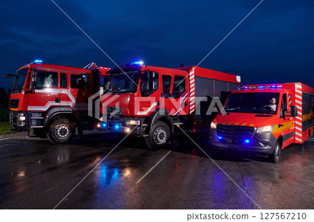 A pair of highly modern and quality fire trucks illuminate the night with their rotating lights, symbolizing the cutting-edge technology and preparedness of the firefighting fleet, ready to respond to 127567210