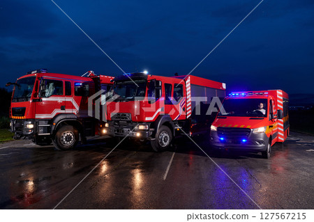 A pair of highly modern and quality fire trucks illuminate the night with their rotating lights, symbolizing the cutting-edge technology and preparedness of the firefighting fleet, ready to respond to A pair of highly modern and quality fire trucks illuminate the night with their rotating lights, symbolizing the cutting-edge technology and preparedness of the firefighting fleet, ready to respond to 127567215