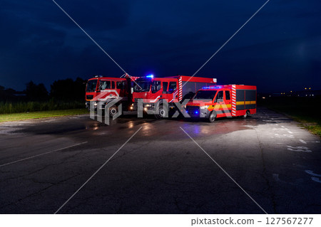 A pair of highly modern and quality fire trucks illuminate the night with their rotating lights, symbolizing the cutting-edge technology and preparedness of the firefighting fleet, ready to respond to 127567277