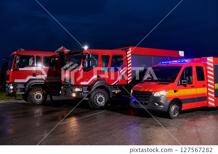 A pair of highly modern and quality fire trucks illuminate the night with their rotating lights, symbolizing the cutting-edge technology and preparedness of the firefighting fleet, ready to respond to 127567282