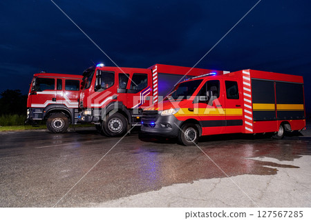 A pair of highly modern and quality fire trucks illuminate the night with their rotating lights, symbolizing the cutting-edge technology and preparedness of the firefighting fleet, ready to respond to 127567285