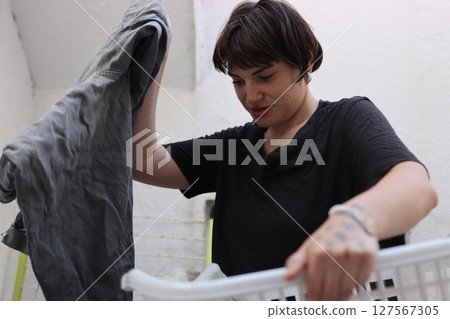Woman putting gray jeans into white laundry basket Woman putting gray jeans into white laundry basket 127567305