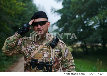 A dedicated soldier salutes his elite unit, showcasing camaraderie and readiness for the most perilous military operations 127567325