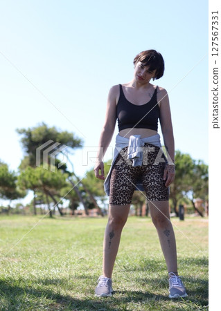 Portrait of a young woman posing in sportswear in a park 127567331