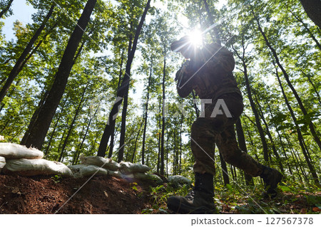 An elite soldier adeptly clears military barriers in the perilous wooded terrain, showcasing tactical skill and agility during specialized training 127567378