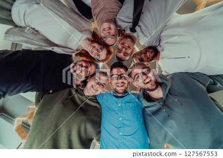 In a modern office, a group of young business professionals is captured in a warm and embracing hug, reflecting the spirit of unity, collaboration, and shared success in their dynamic workplace. In a modern office, a group of young business professionals is captured in a warm and embracing hug, reflecting the spirit of unity, collaboration, and shared success in their dynamic workplace. 127567553