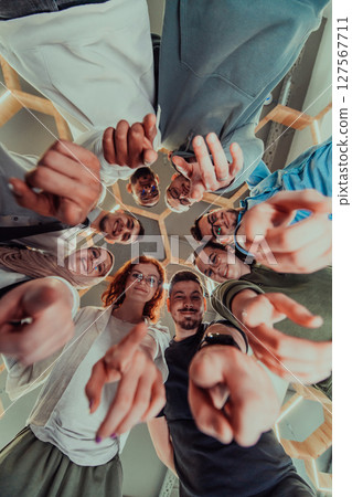 In a modern office, a group of young business professionals is captured in a warm and embracing hug, reflecting the spirit of unity, collaboration, and shared success in their dynamic workplace. 127567711