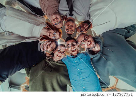 In a modern office, a group of young business professionals is captured in a warm and embracing hug, reflecting the spirit of unity, collaboration, and shared success in their dynamic workplace. 127567751