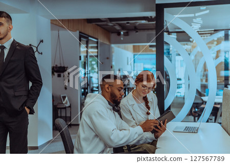 In a modern office setting, an African American businessman and his Muslim colleague, wearing a hijab, engage in collaborative discussions, tackling various business tasks and solving problems 127567789
