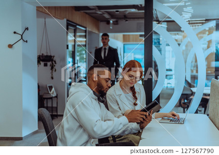 In a modern office setting, an African American businessman and his Muslim colleague, wearing a hijab, engage in collaborative discussions, tackling various business tasks and solving problems 127567790
