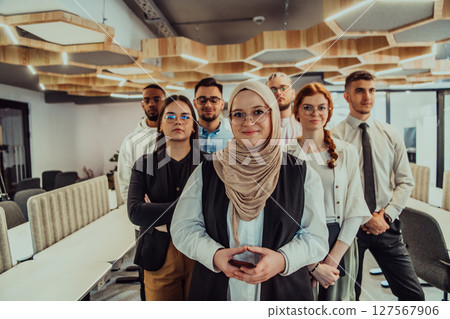A group of young business professionals stands together, taking a well-deserved break from their busy workday, showcasing camaraderie, teamwork, and a moment of relaxation in their dynamic workplace 127567906