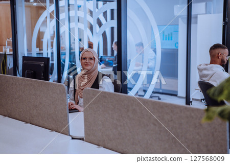 In a modern office setting, an African American businessman and his Muslim colleague, wearing a hijab, engage in collaborative discussions, tackling various business tasks and solving problems In a modern office setting, an African American businessman and his Muslim colleague, wearing a hijab, engage in collaborative discussions, tackling various business tasks and solving problems 127568009