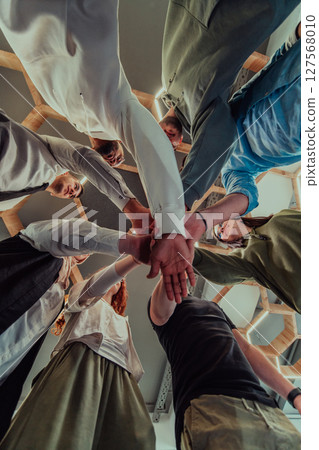 A group of young businessmen offer their hands together, symbolizing togetherness in the business world A group of young businessmen offer their hands together, symbolizing togetherness in the business world 127568010