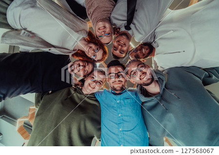 In a modern office, a group of young business professionals is captured in a warm and embracing hug, reflecting the spirit of unity, collaboration, and shared success in their dynamic workplace. 127568067