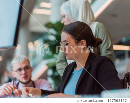In a modern startup office, a diverse group of young professionals collaboratively tackles various business problems and challenges, surrounded by their engaged colleagues, fostering innovation and 127568152