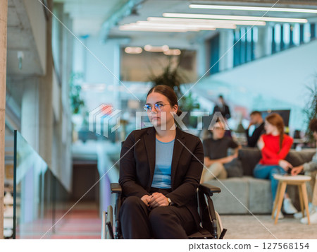 In a modern office, a young businesswoman in a wheelchair is surrounded by her supportive colleagues, embodying the spirit of inclusivity and diversity in the workplace 127568154