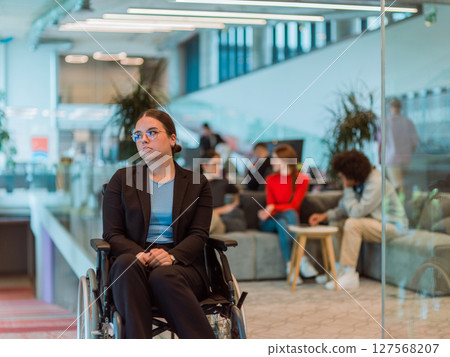 In a modern office, a young businesswoman in a wheelchair is surrounded by her supportive colleagues, embodying the spirit of inclusivity and diversity in the workplace In a modern office, a young businesswoman in a wheelchair is surrounded by her supportive colleagues, embodying the spirit of inclusivity and diversity in the workplace 127568207