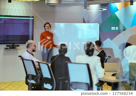 A pregnant business woman with orange hair confidently presents her business plan to colleagues in a modern glass office, embodying entrepreneurship and innovation 127568234