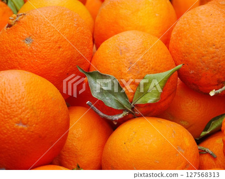 A bunch of oranges with a leaf on top 127568313