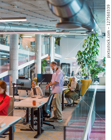 In a modern startup office, a diverse group of young professionals collaboratively tackles various business problems and challenges, surrounded by their engaged colleagues, fostering innovation and 127568339