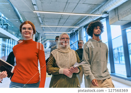 In the sleek corridors of a modern startup office, a diverse group of colleagues, led by their director, confidently stride forward, symbolizing collective success and the journey toward new business 127568369