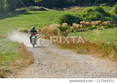 A professional motocross rider exhilaratingly riding a treacherous off-road forest trail on their motorcycle. A professional motocross rider exhilaratingly riding a treacherous off-road forest trail on their motorcycle. 127568512