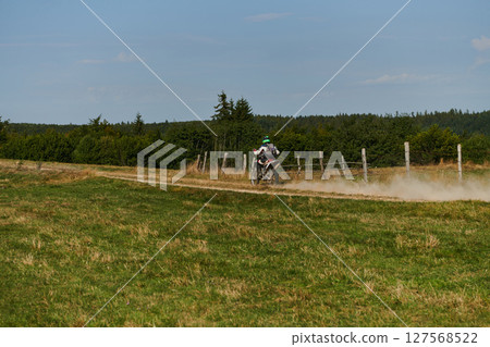 A professional motocross rider exhilaratingly riding a treacherous off-road forest trail on their motorcycle. 127568522