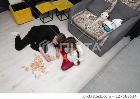 Playing together on a cozy floor in a modern living room with a game of wooden blocks as laughter fills the air and creativity takes flight during the afternoon hours 127568534