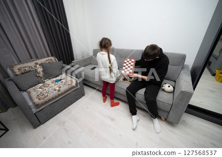 Engaging in a thoughtful chess match inside a cozy living room with modern decor and soft lighting during a quiet afternoon Engaging in a thoughtful chess match inside a cozy living room with modern decor and soft lighting during a quiet afternoon 127568537